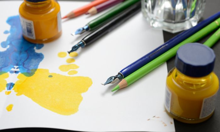 Bunte Farbkleckse und Bundstifte auf Papier